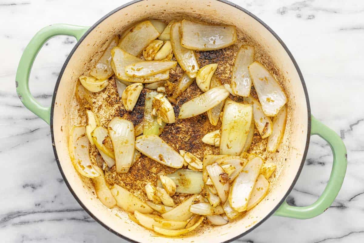 Sliced onions, garlic, and ginger in a large pan.
