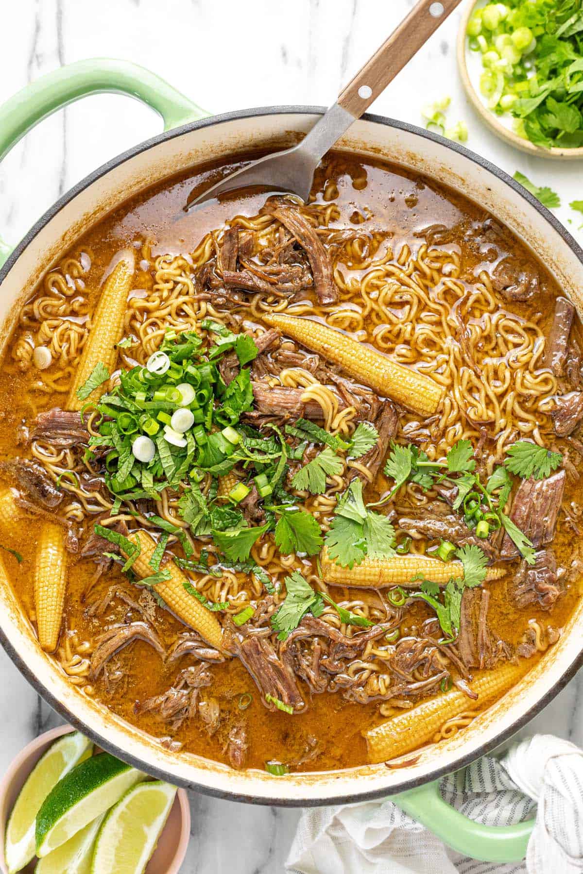 Large pot filled with shredded beef ramen garnished with cilantro and green onion.