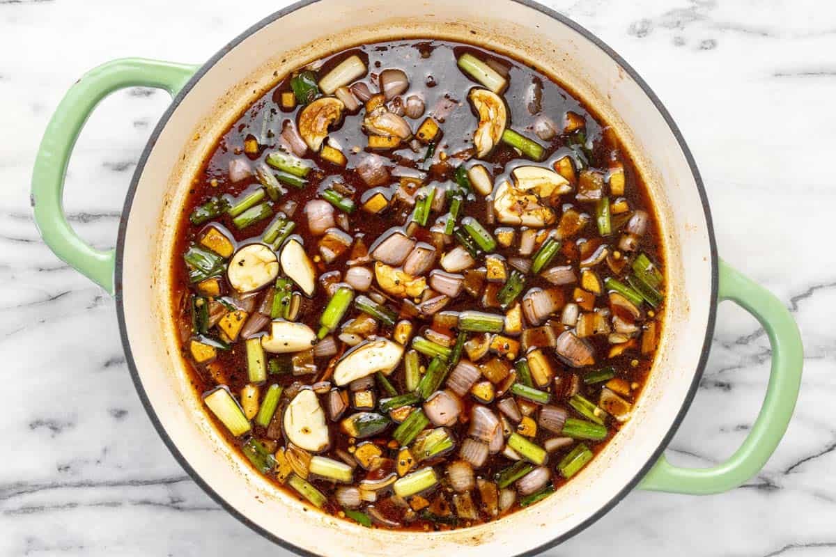 Sauteed veggies in a soy sauce based broth in a pan.