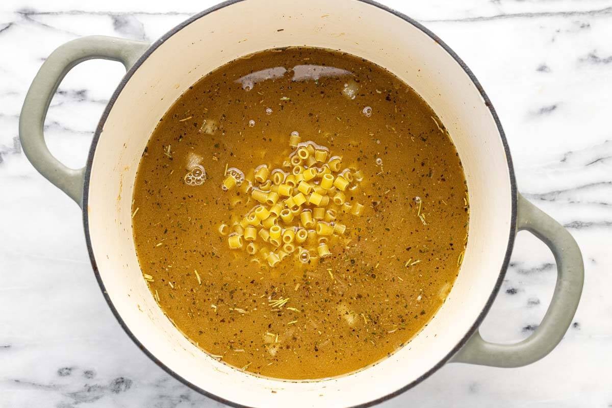 Broth and noodles in a large soup pot.