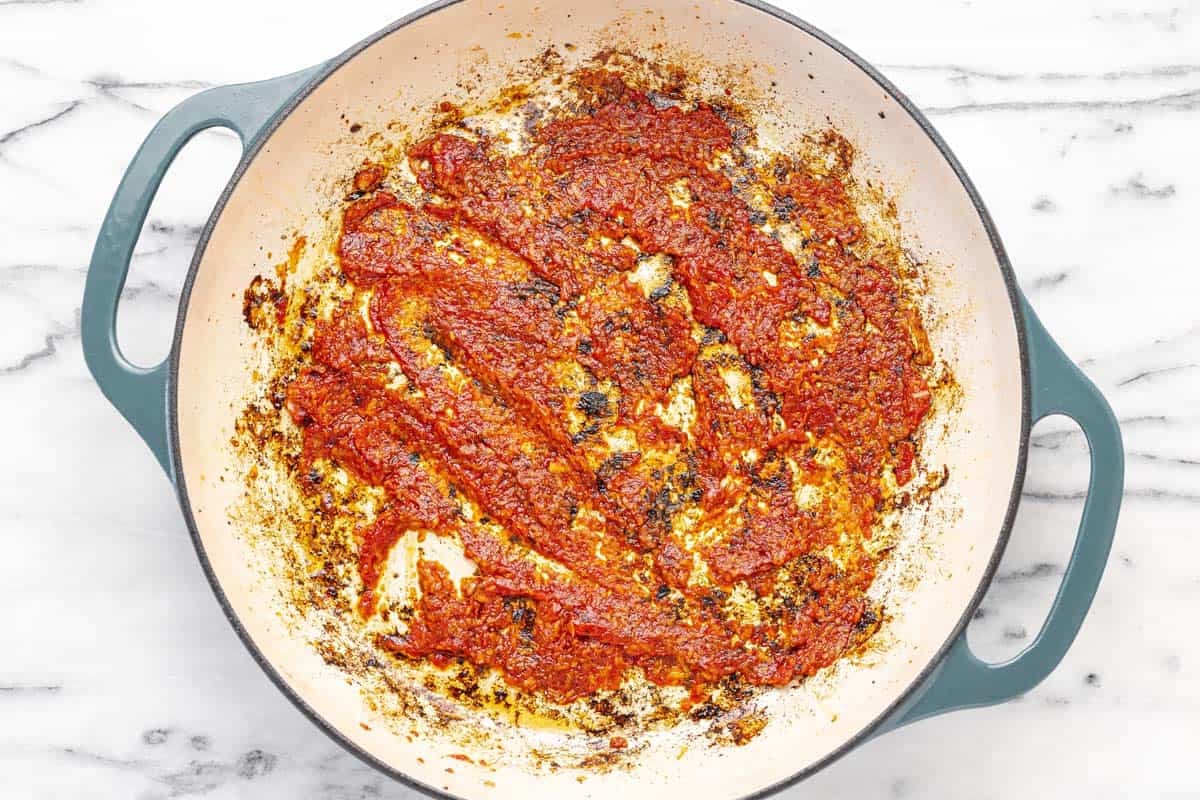 Garlic and tomato paste cooked in a large pan.