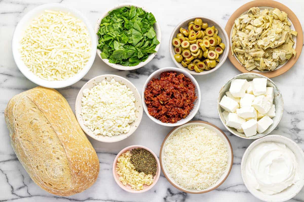Bowls of ingredients to make cheesy Greek garlic bread.