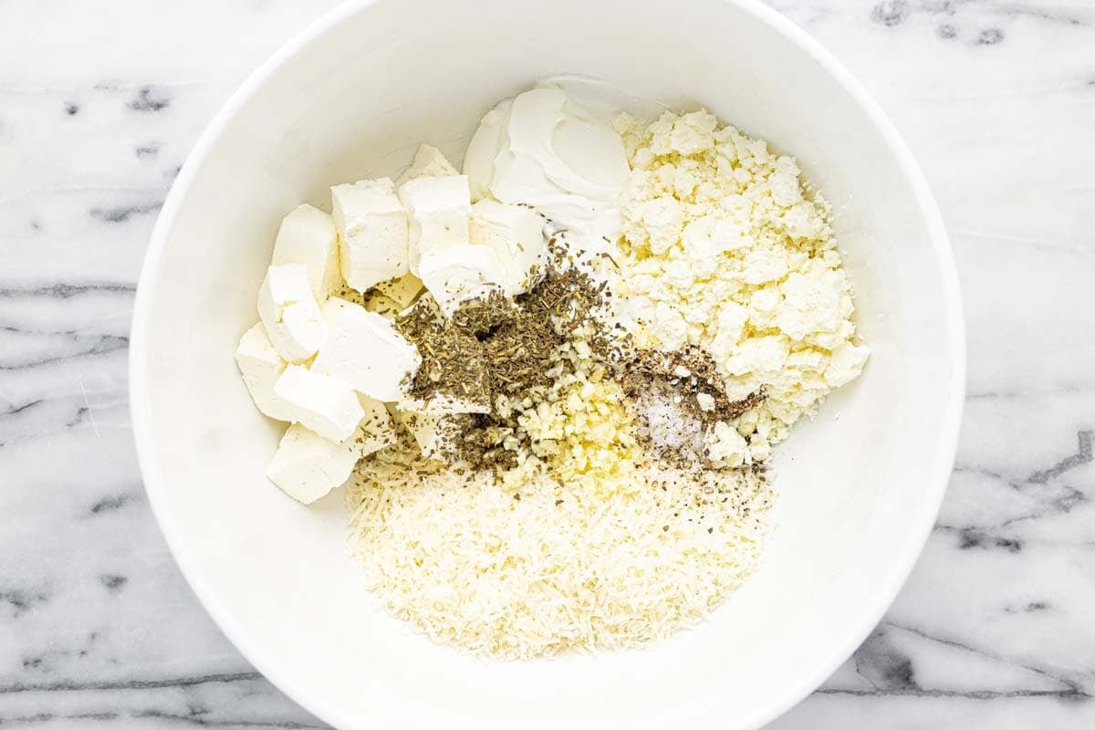 Bowl of ingredients to make the creamy base of Greek garlic cheese bread.