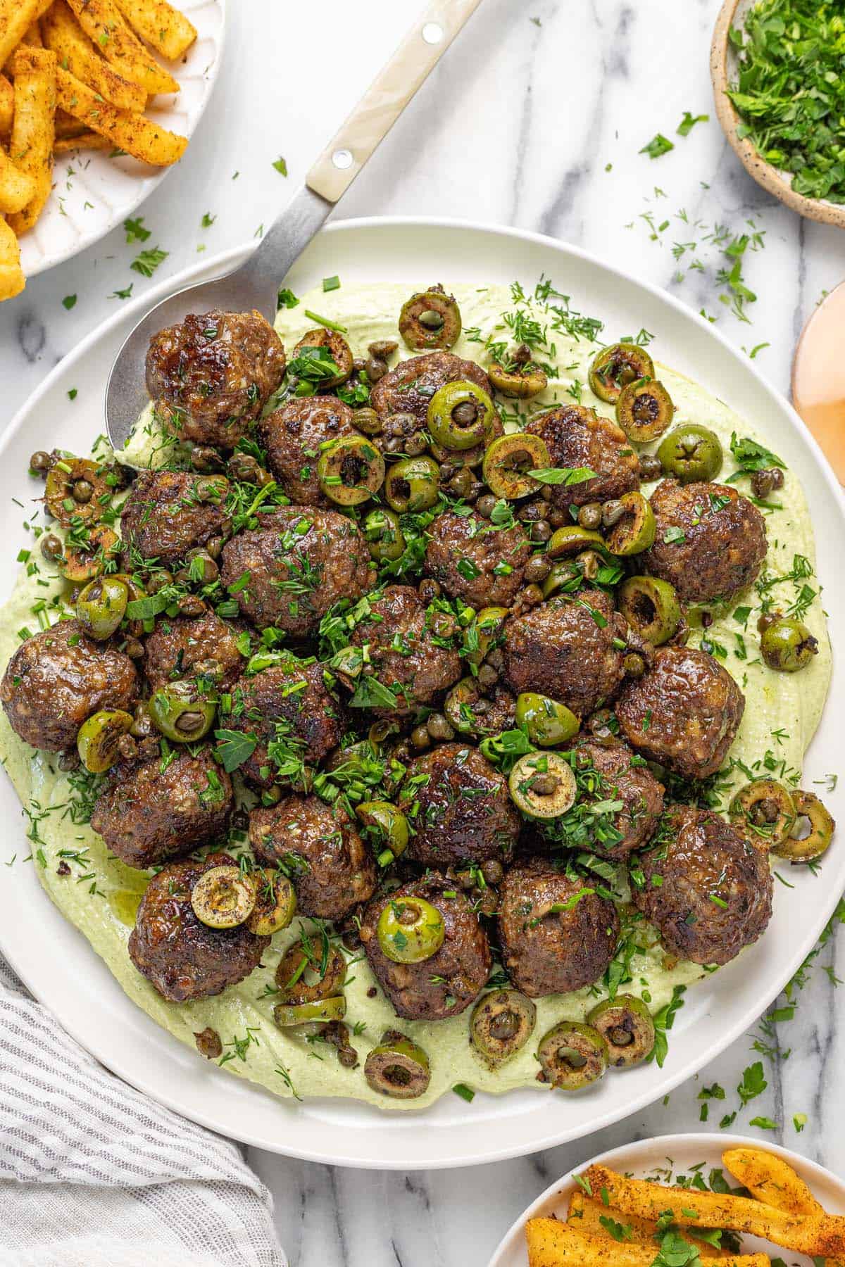Large plate filled with whipped feta, meatballs, and olives. 