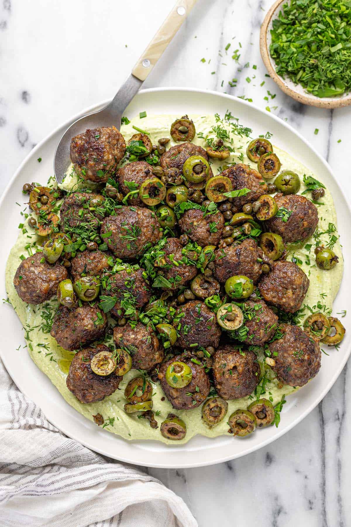 Large plate filled with whipped feta, meatballs, and olives.