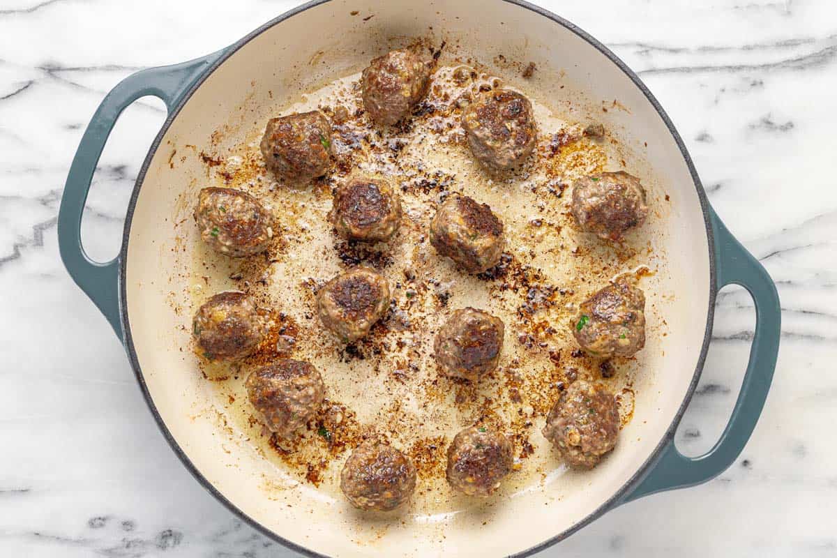 Seared meatballs in a large pan.