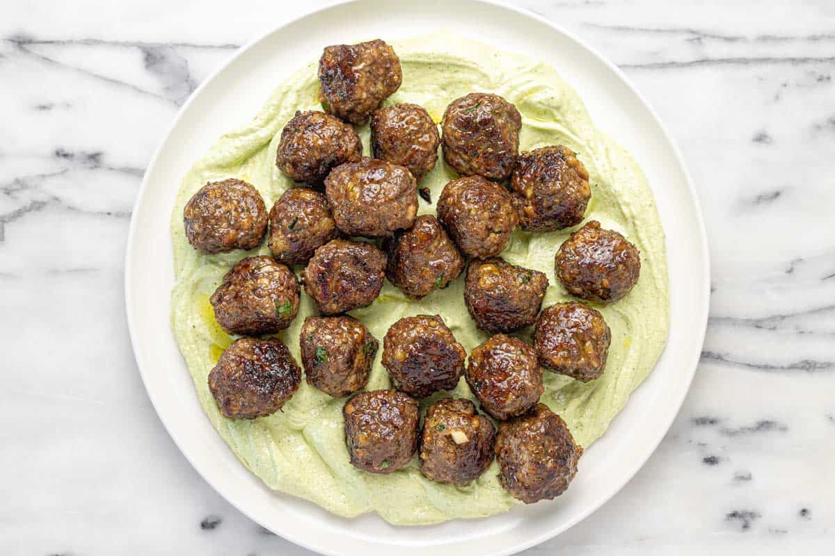 Juicy meatballs on a bed of whipped feta on a serving platter.