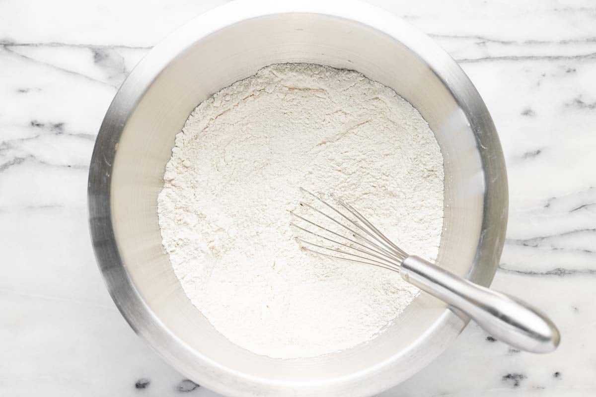 Dry ingredients in a bowl with a whisk for the cobbler topping.