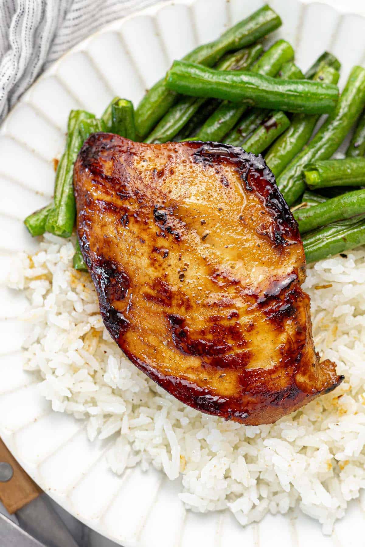 Plate with a cooked chicken breast, green beans, and rice.