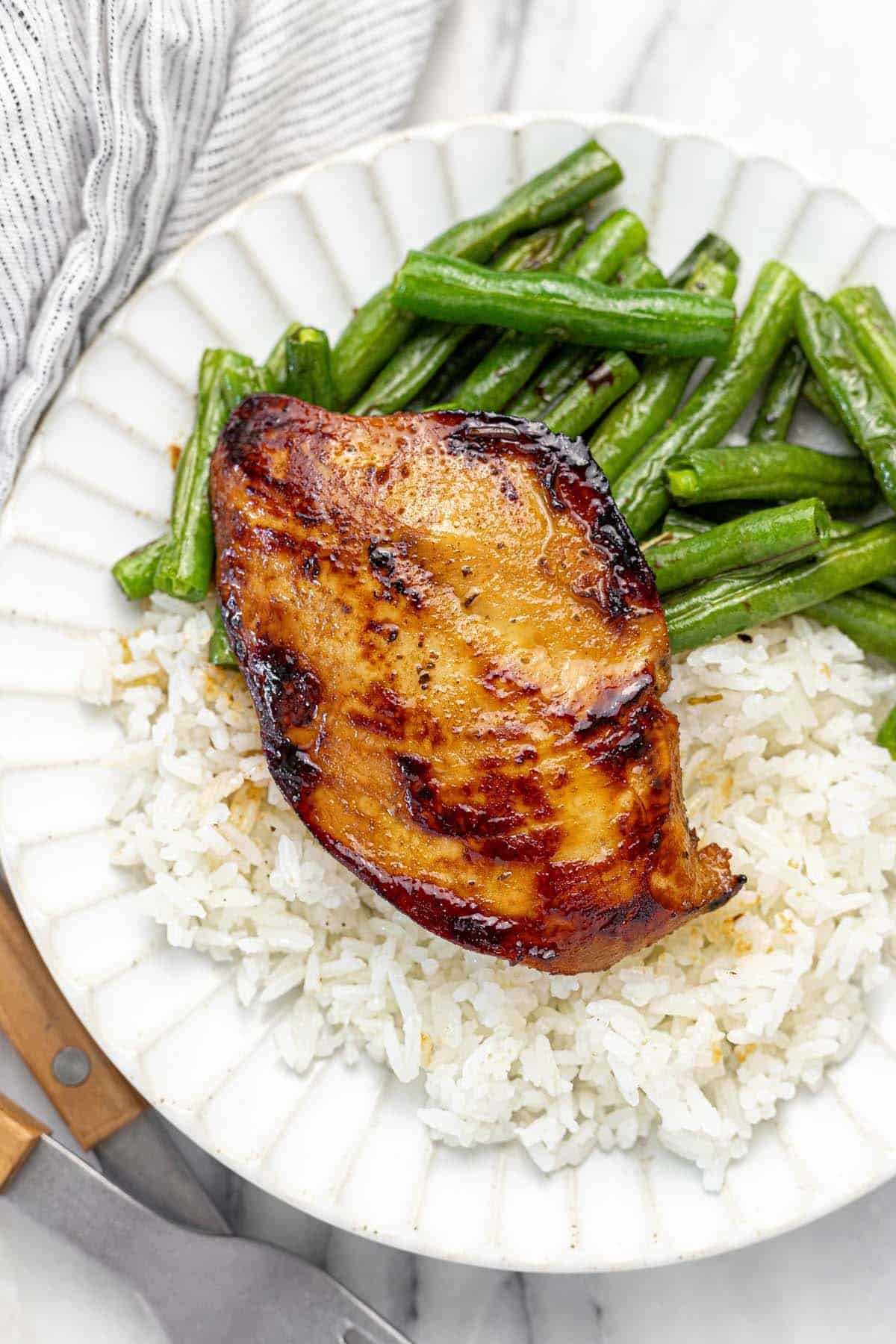 Plate with a cooked chicken breast, green beans, and rice.