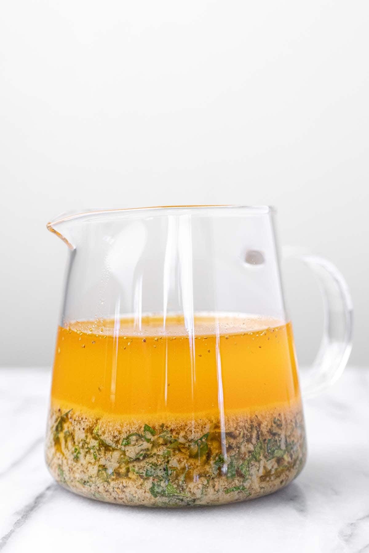 Marinated chickpea salad dressing in a small glass pitcher.