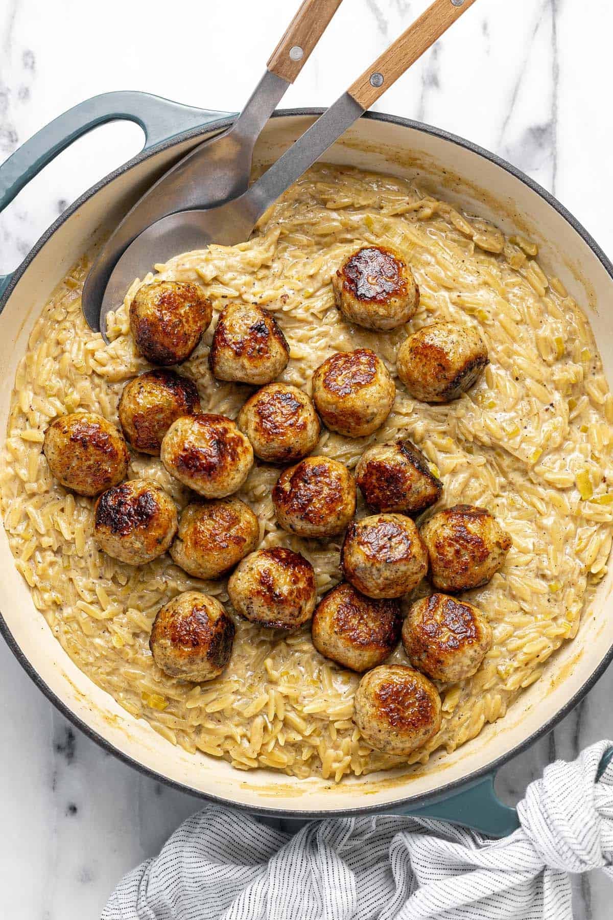 Large pan filled with chicken meatballs and cheesy orzo pasta.