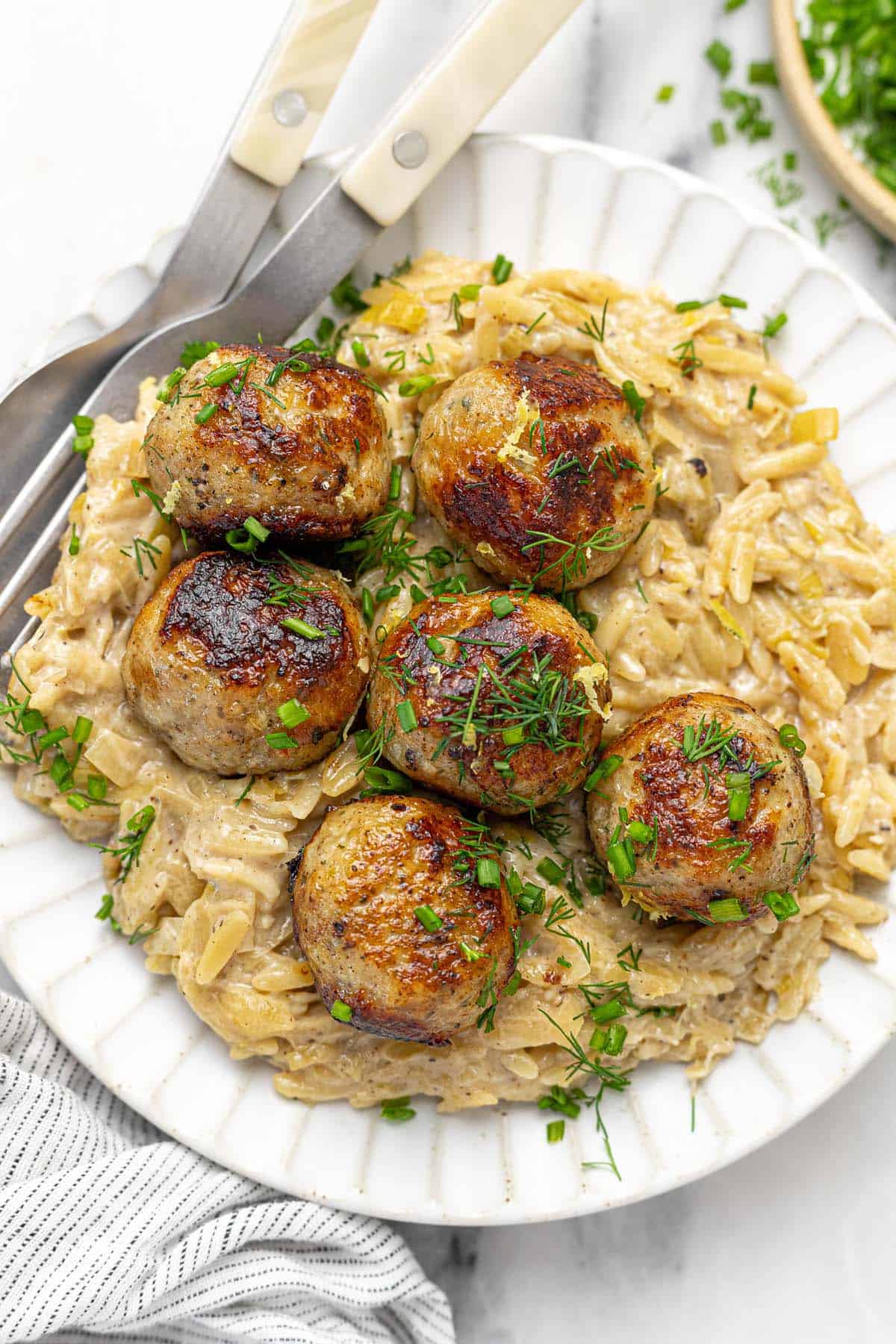 Plate filled with cheesy orzo and sauteed chicken meatballs.
