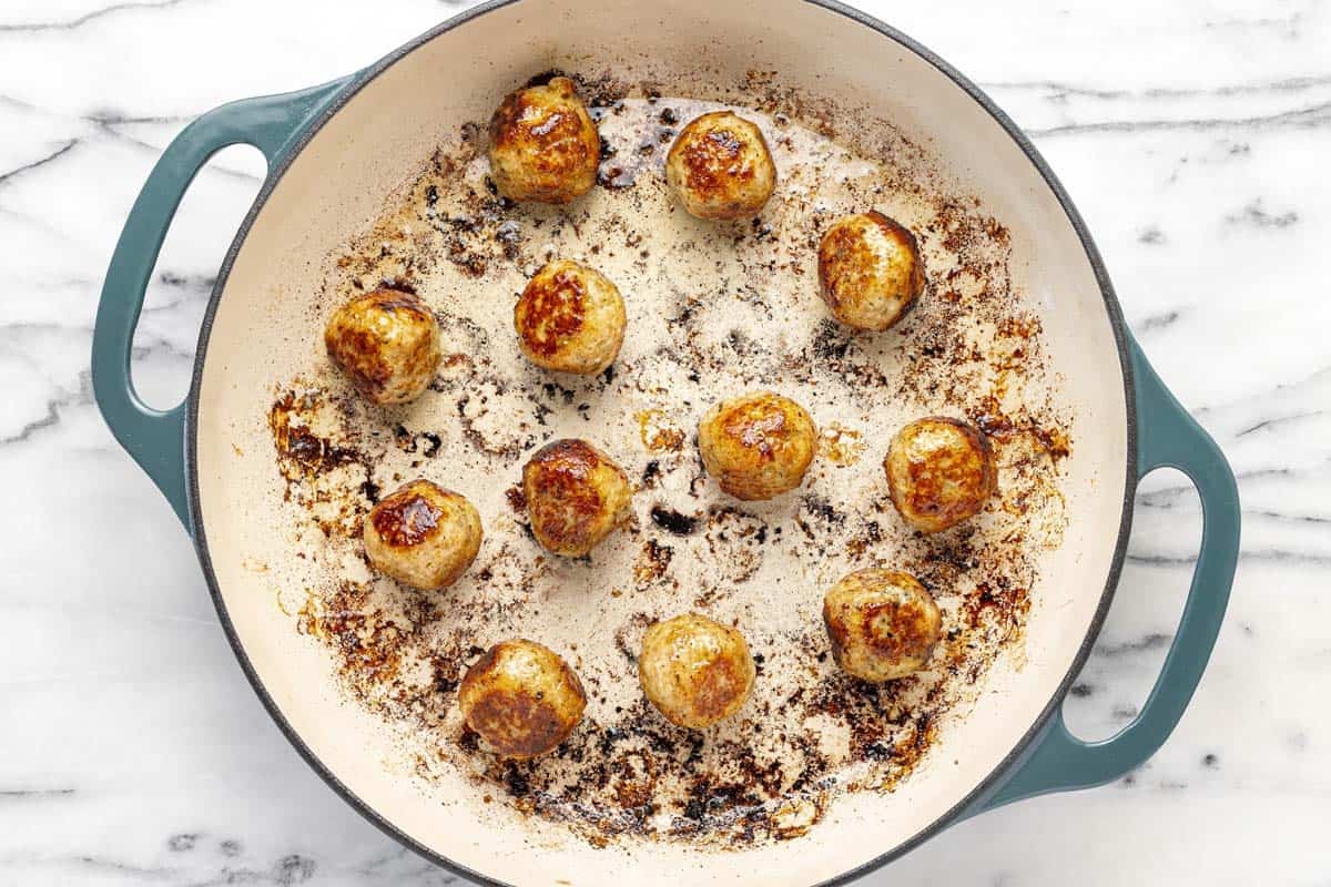 Large pan filled with sauteed chicken meatballs.