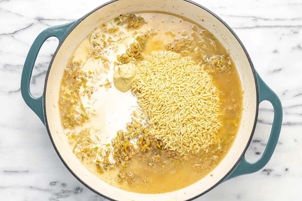 Orzo, chicken stock, Dijon, and half and half in a large pan with leeks.