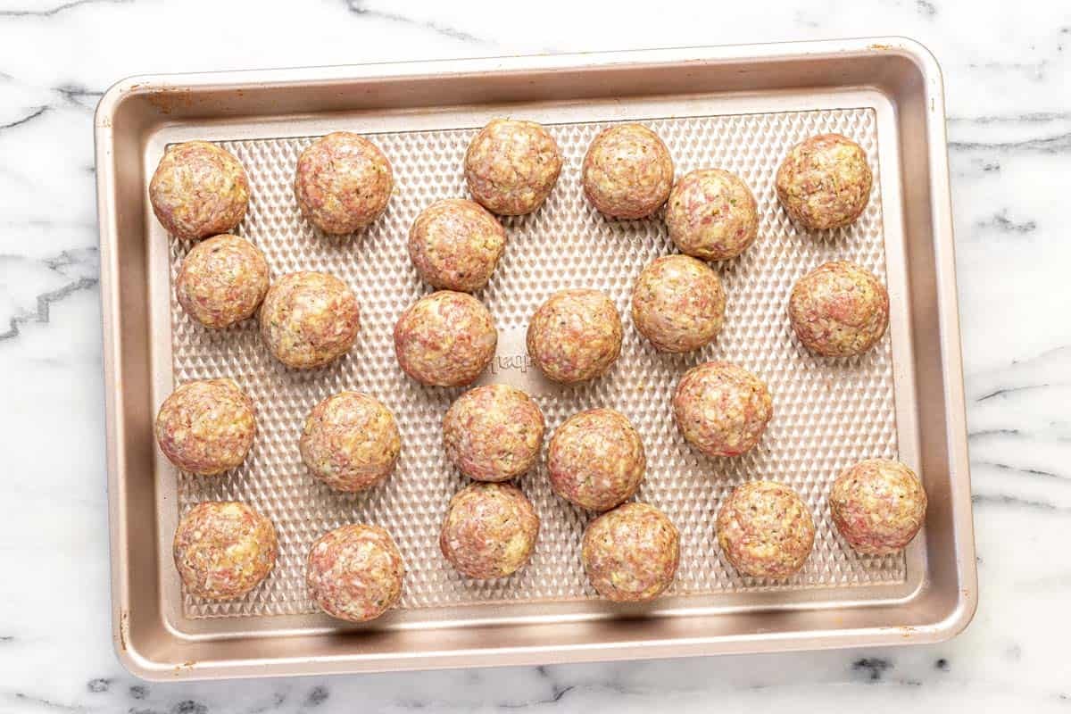 Ground beef meatballs on a large baking sheet.