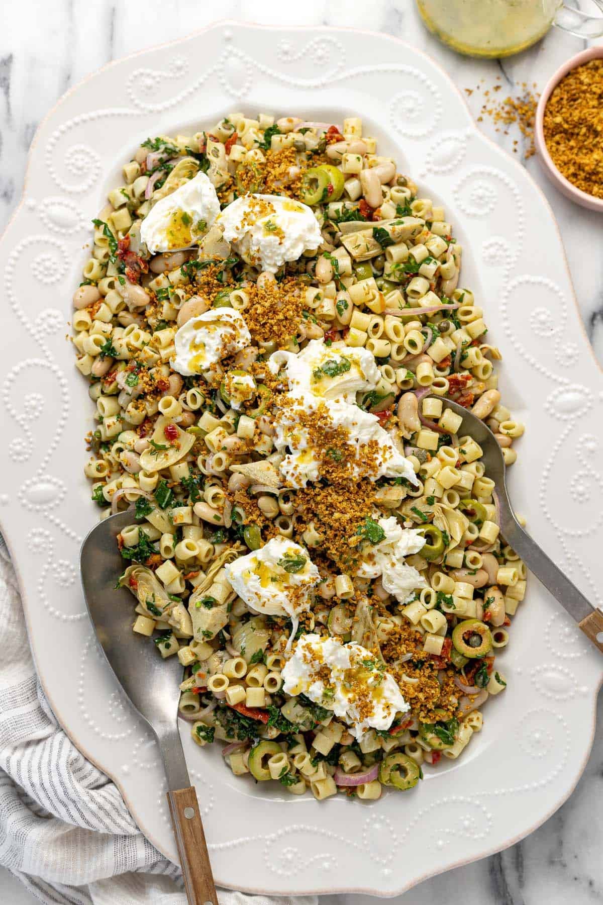Large platter filled with marinated white bean pasta salad topped with burrata. 