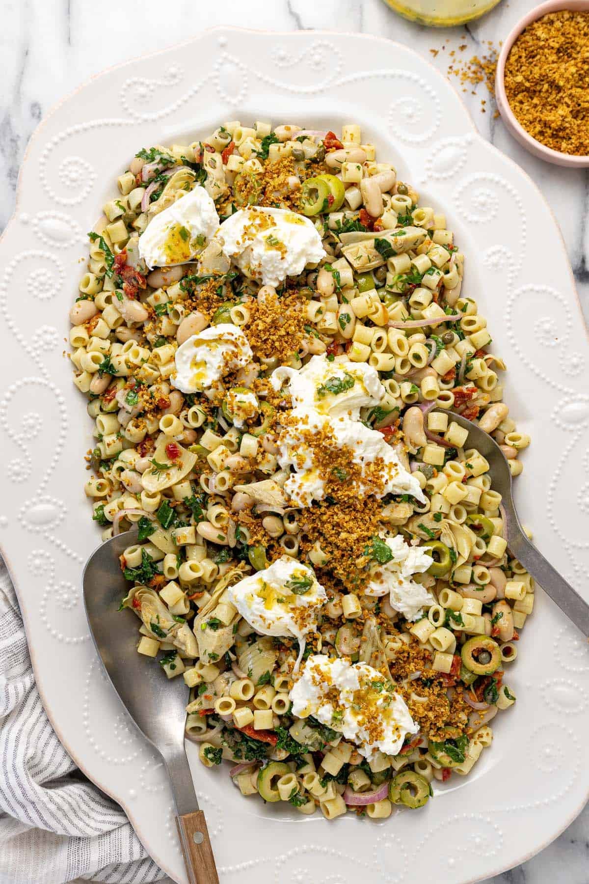 Large platter filled with marinated white bean pasta salad topped with burrata.
