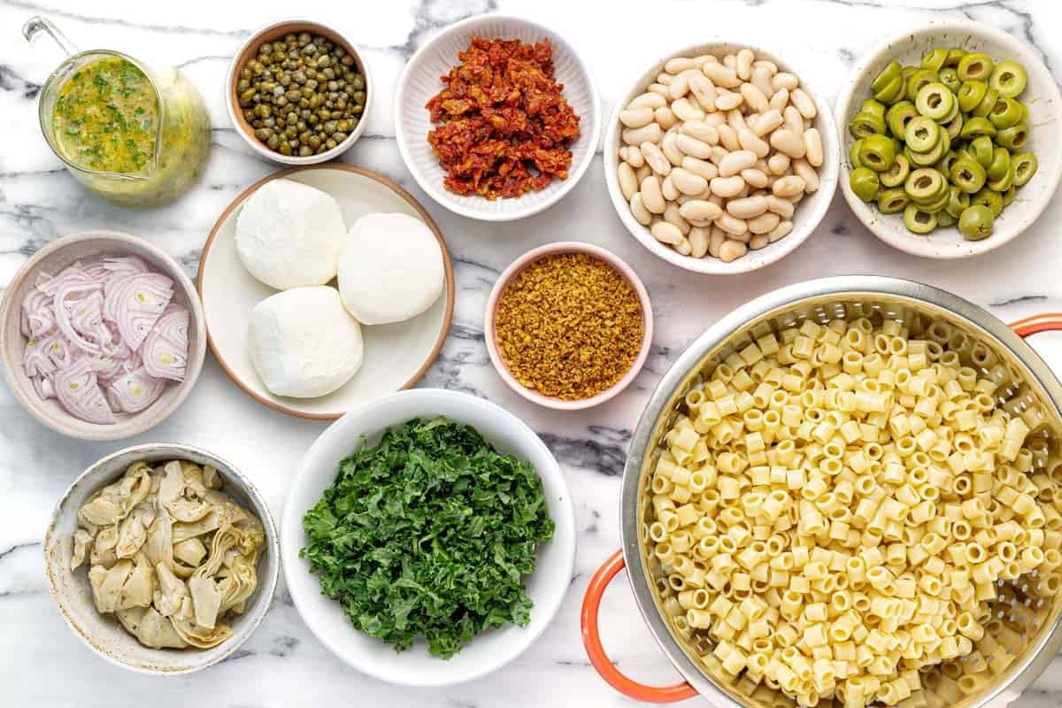 Bowls of ingredients to make marinated white bean pasta salad.
