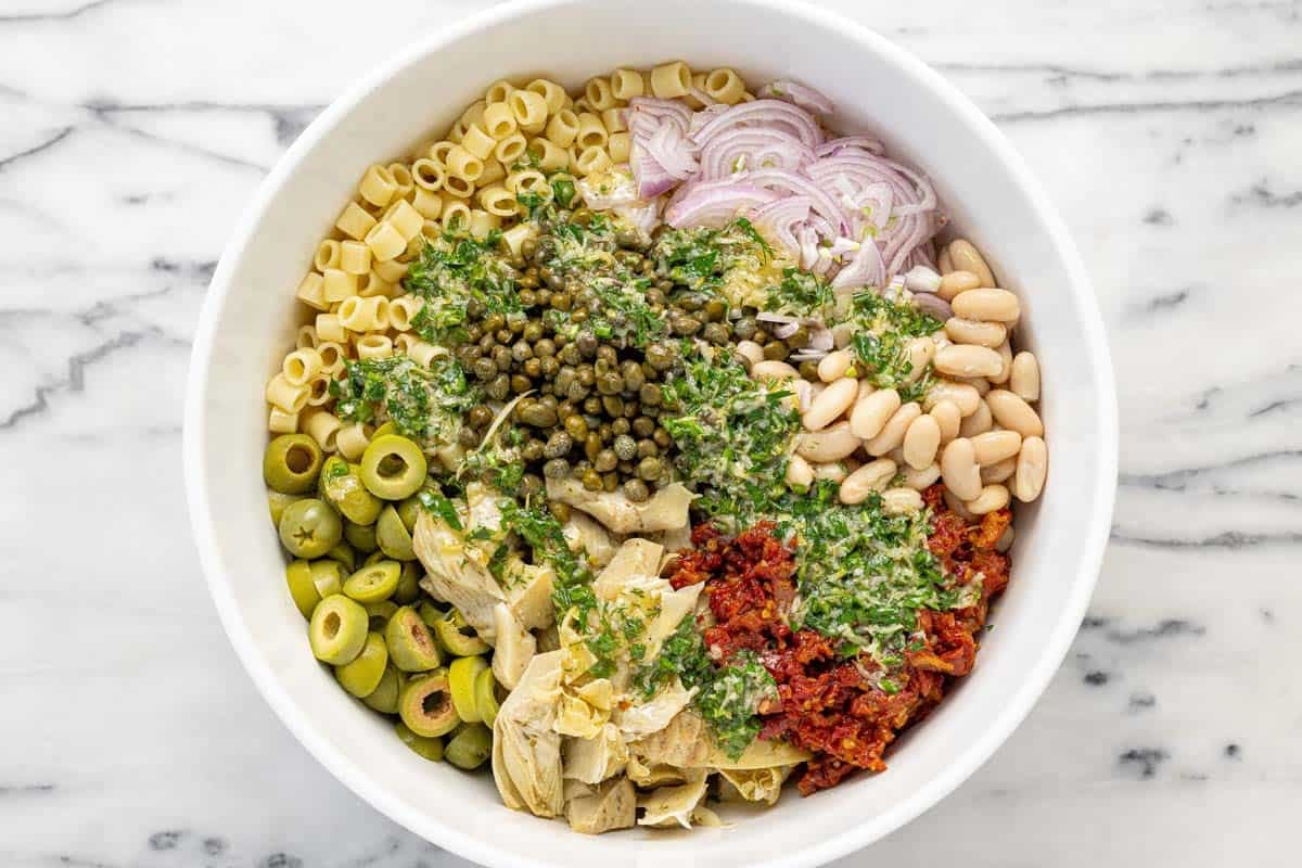 Dressing drizzled over a white bean pasta salad in a bowl.