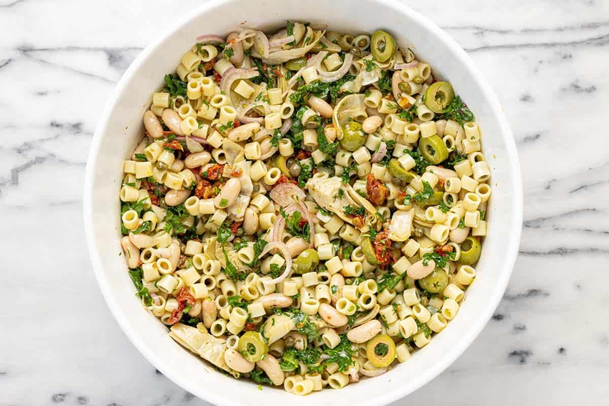 Large bowl filled with marinated white bean pasta salad.