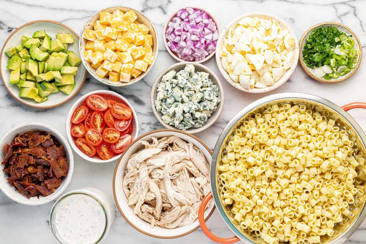 Bowls of ingredients to make cobb pasta salad.
