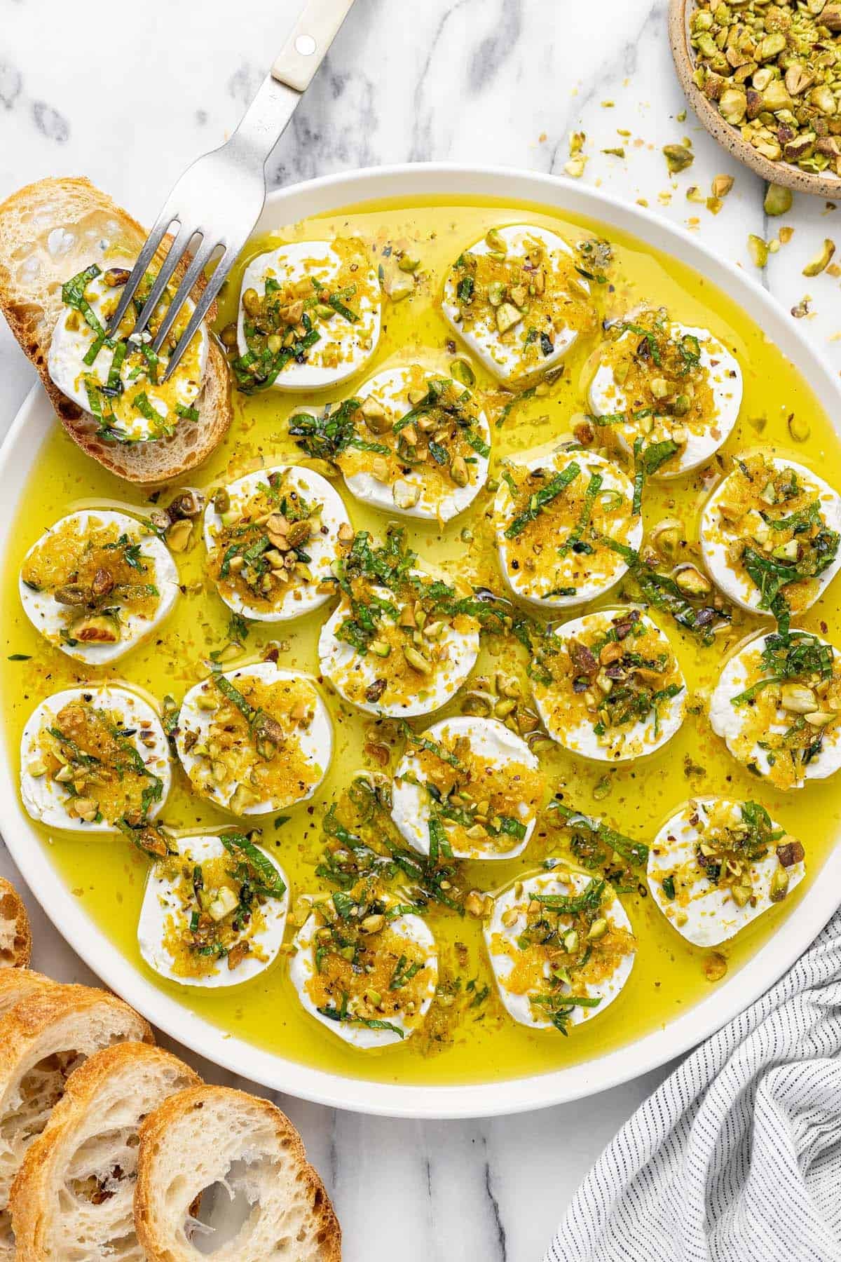 Plate of marinated goat cheese topped with orange zest, mint, and pistachios.