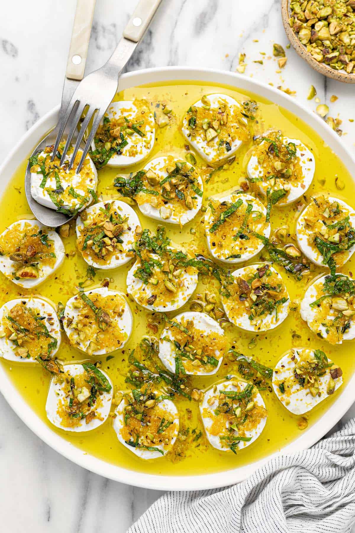 Plate of marinated goat cheese topped with orange zest, mint, and pistachios.