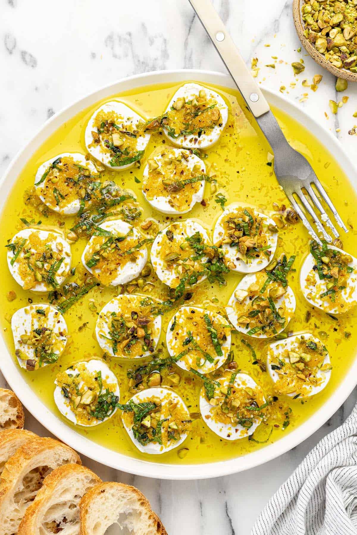 Plate of marinated goat cheese topped with orange zest, mint, and pistachios.