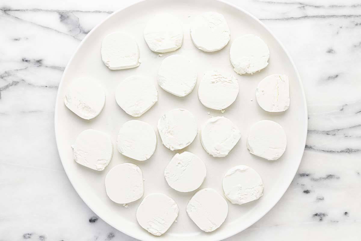 Large plate with slices of goat cheese on it.