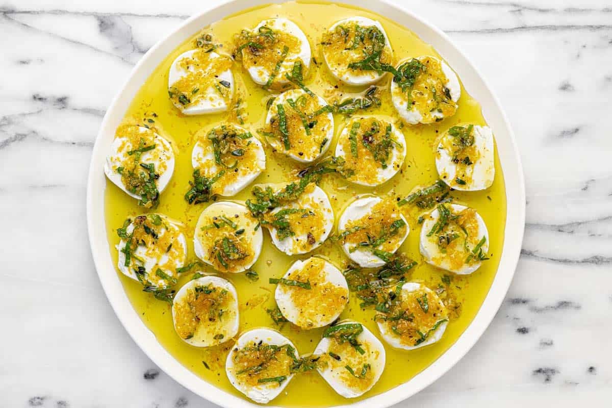 Plate of marinated goat cheese topped with orange zest and mint.
