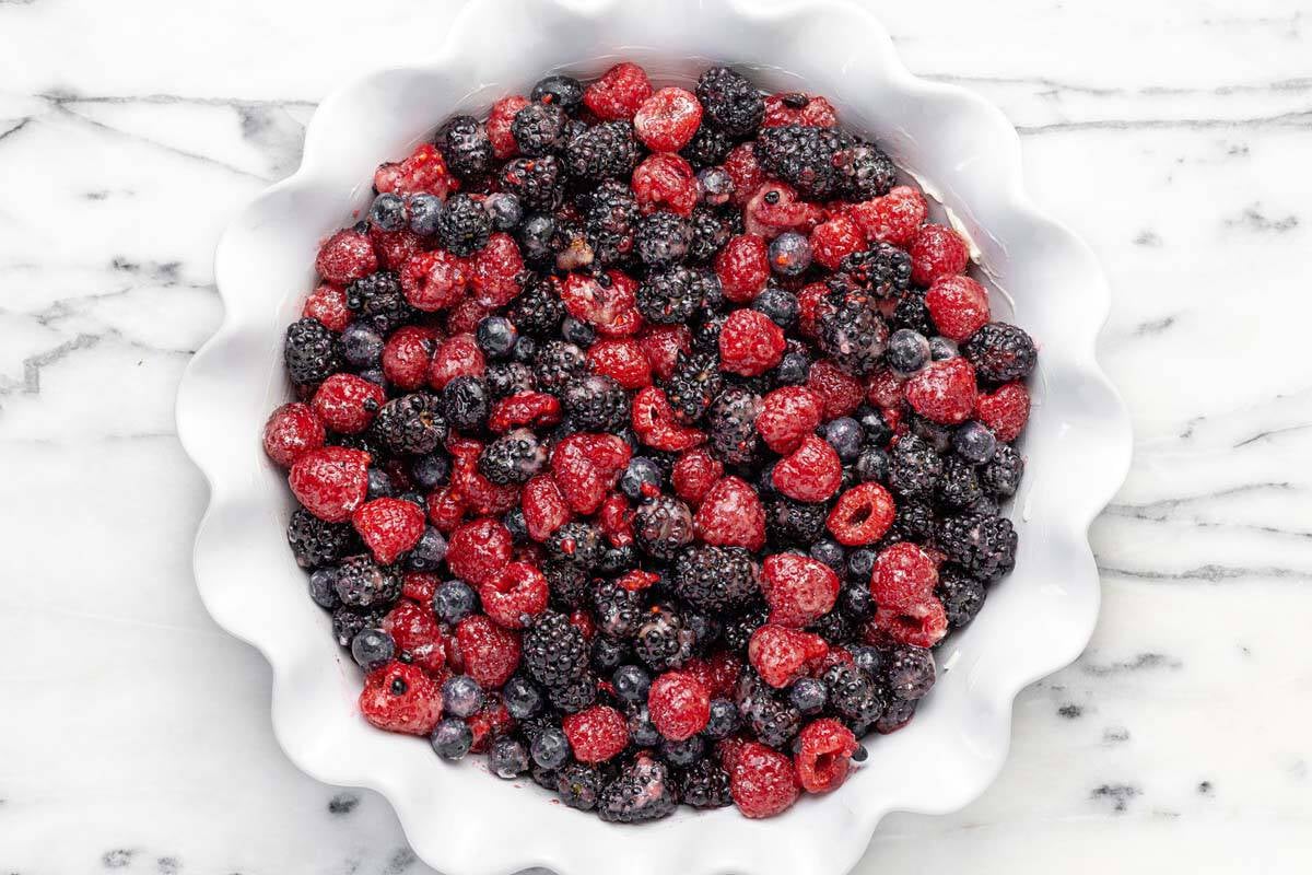 Large pie dish filled with berry tossed in cornstarch, sugar, vanilla, salt, and lemon juice.