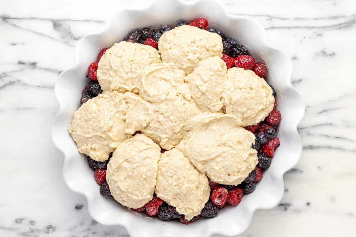 Triple berry cobbler with homemade topping in a pie dish.