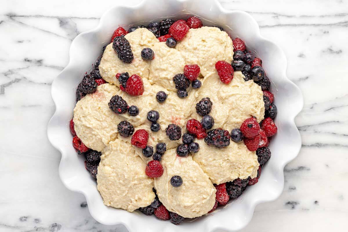 Homemade berry cobbler in a pie dish ready to go in the oven.
