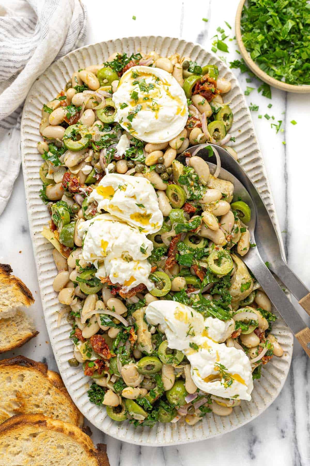 Large serving platter with marinated white bean salad garnished with burrata.