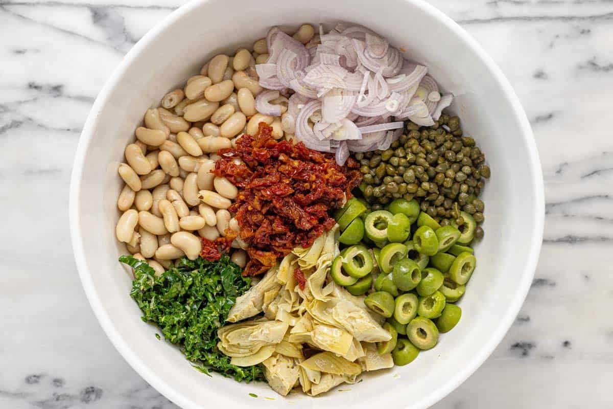 Large bowl filled with ingredients for white bean salad.