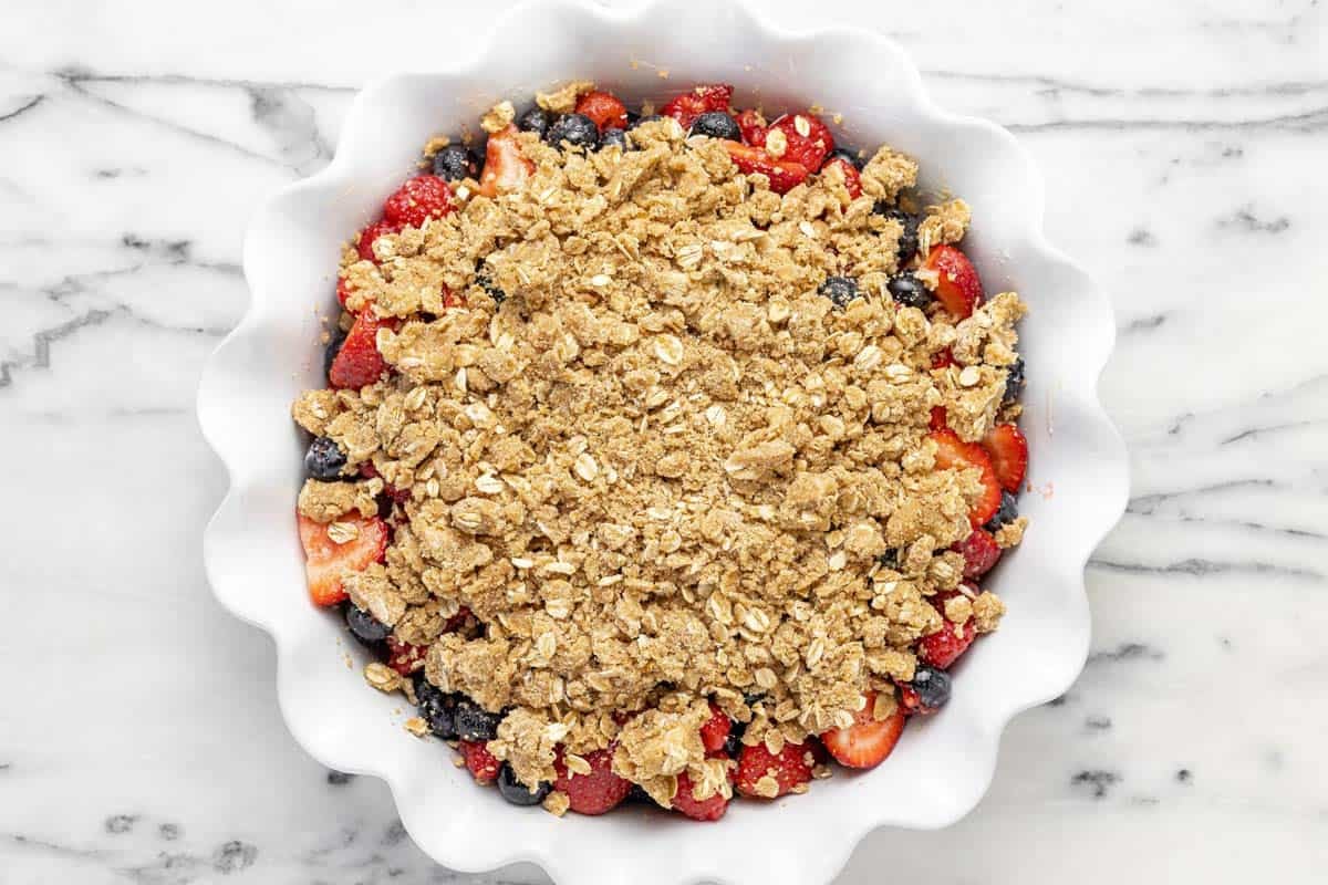 Deep dish pie pan filled with berries and homemade crisp topping.