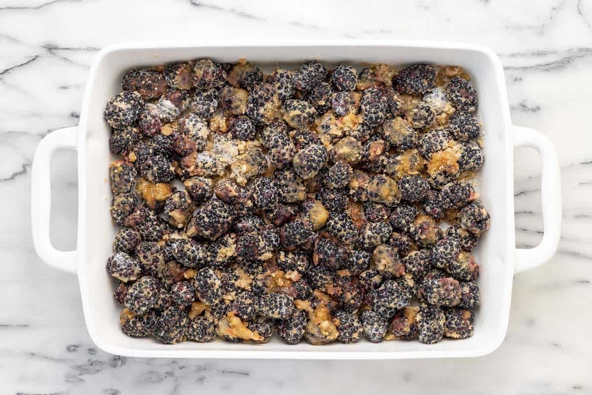 Blackberries coated in sugar, corn starch, and lemon juice in a large baking dish.