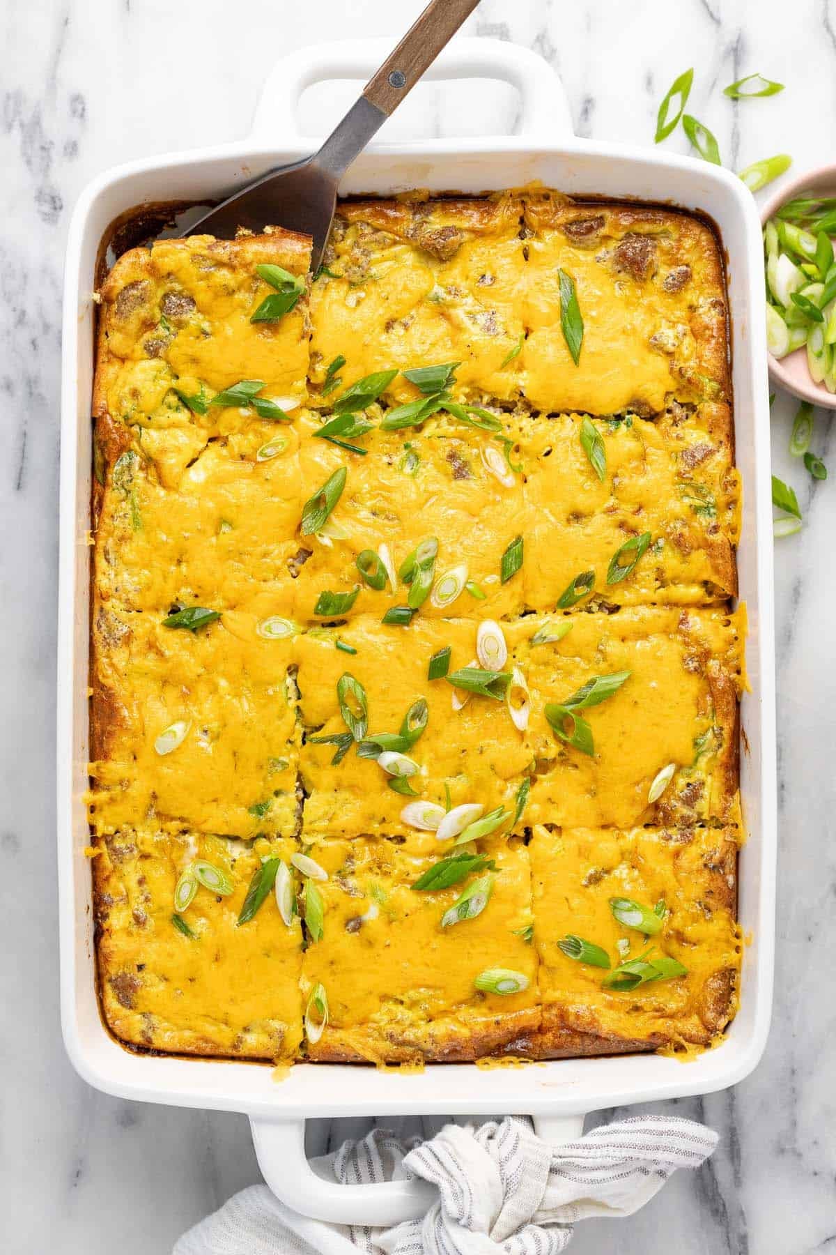 Large baking dish filled with homemade breakfast casserole recipe topped with green onion.