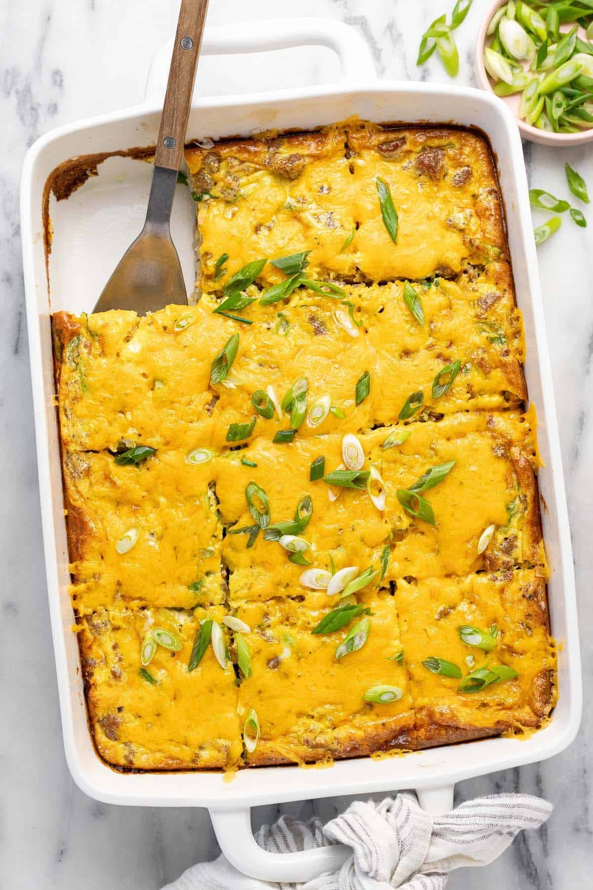 Large baking dish filled with homemade breakfast casserole recipe topped with green onion.