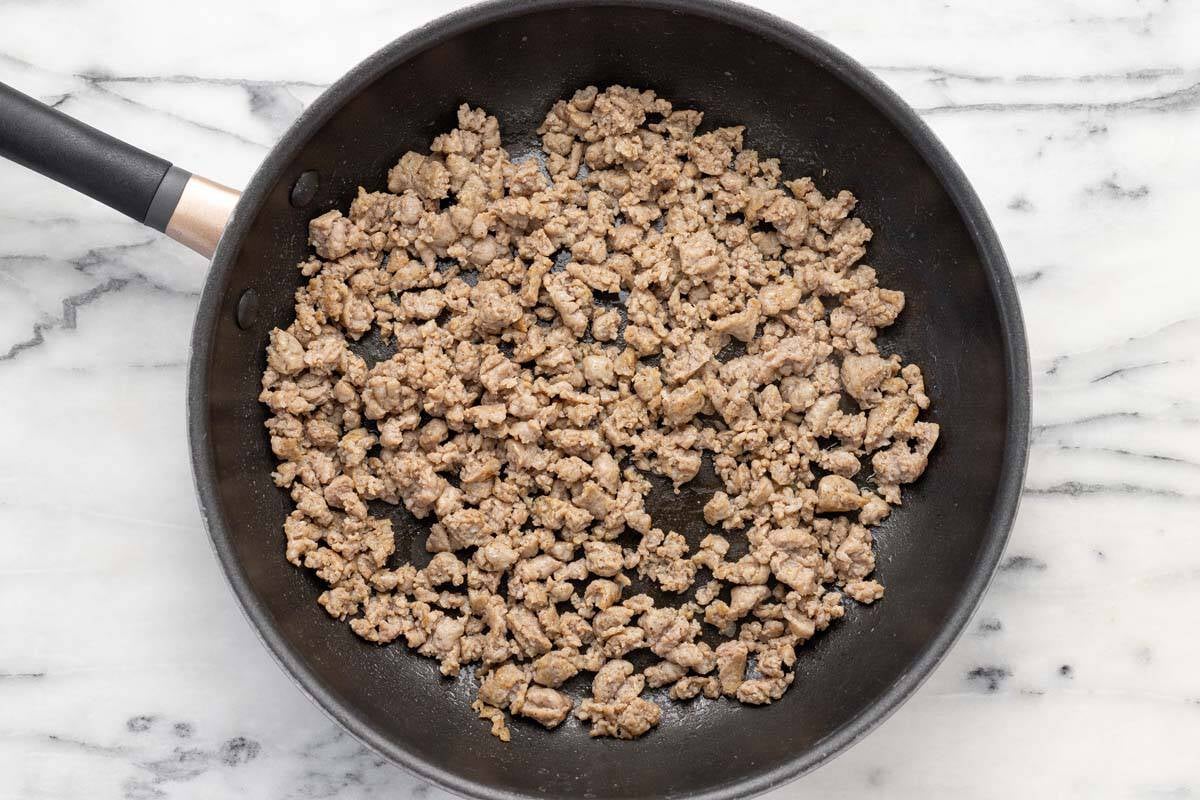 Large saute pan filled with ground sausage.
