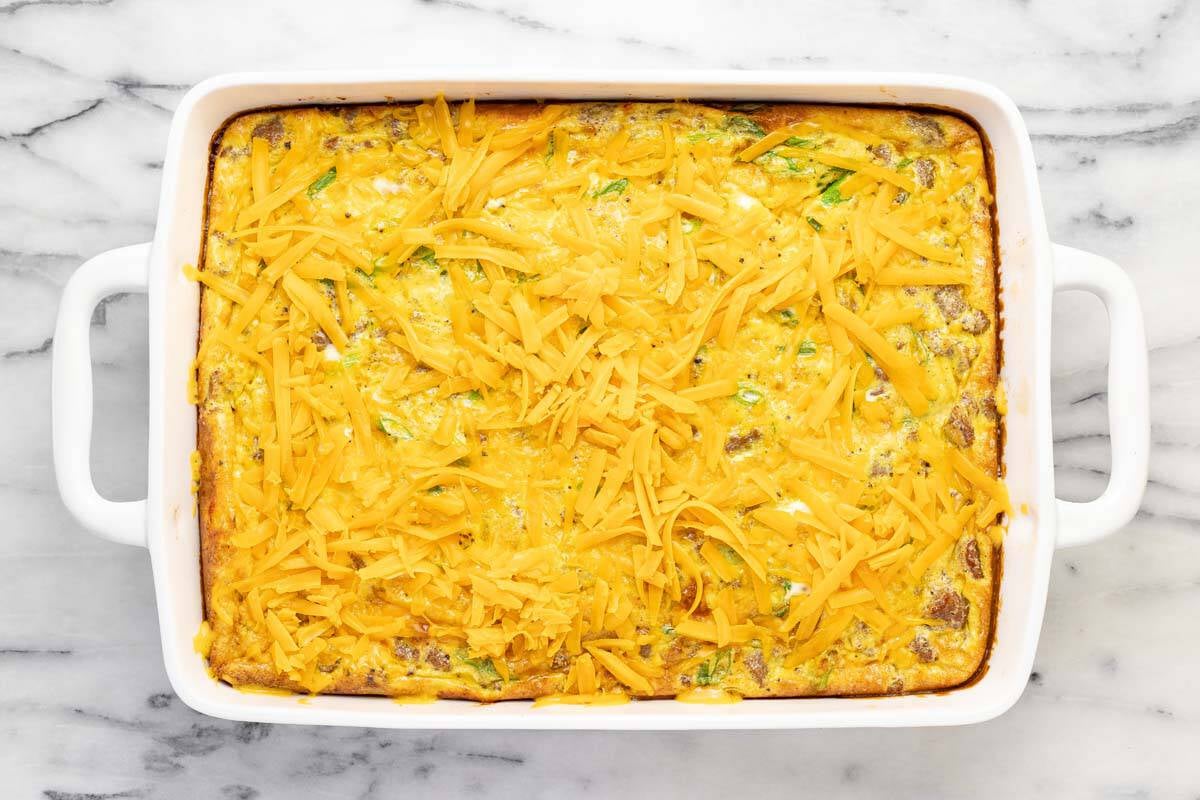 Breakfast casserole topped with shredded cheese.