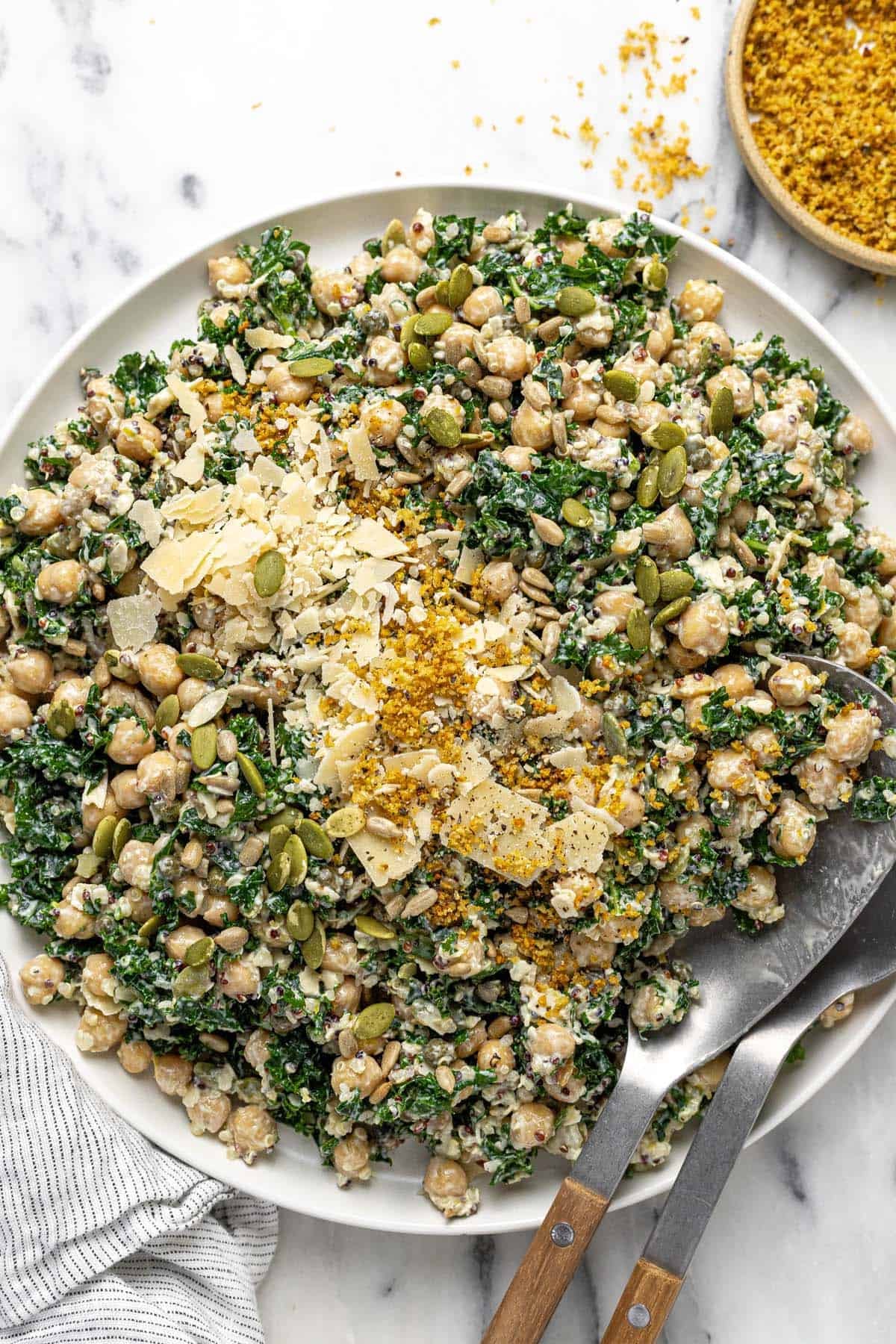 Large plate filled with dense bean Caesar salad garnished with Parmesan, breadcrumbs, and pumpkin seeds.