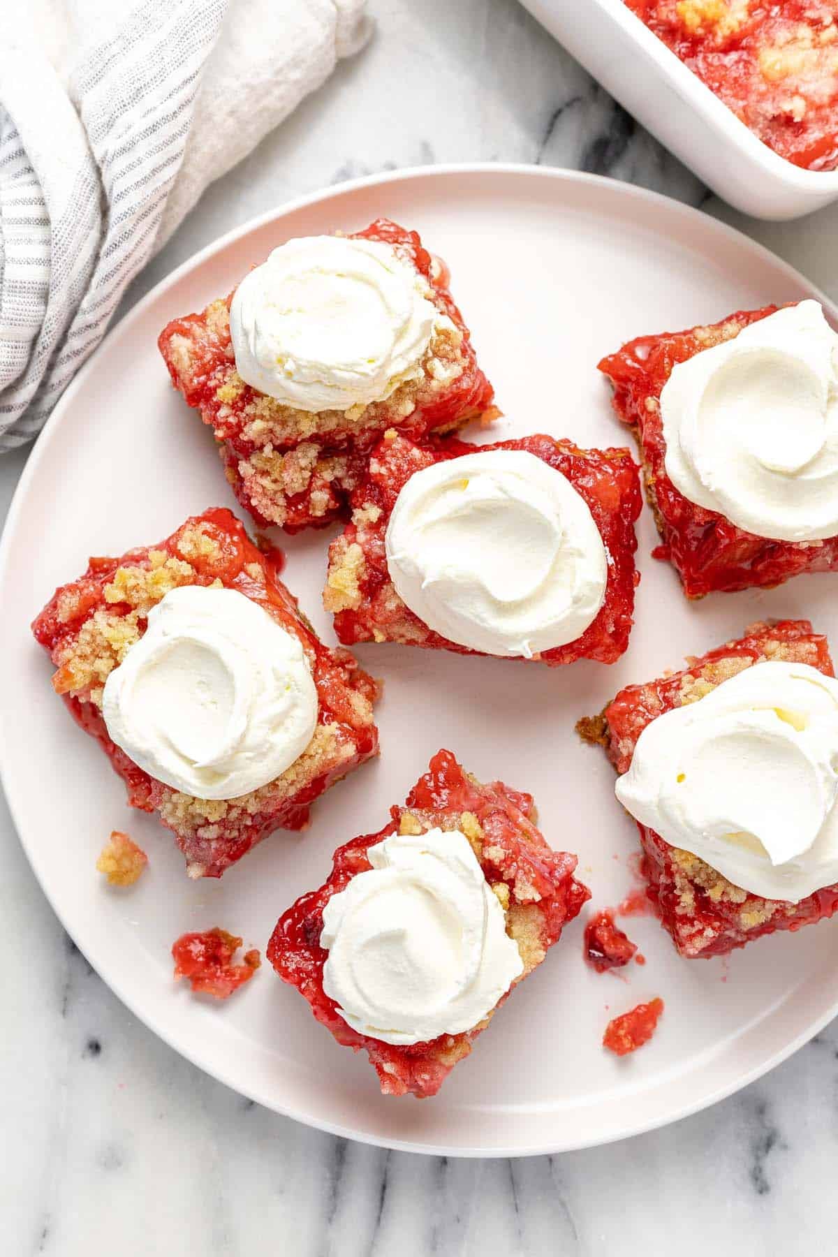 Round plate filled with slices of rhubarb jello dessert topped with whipped cream.