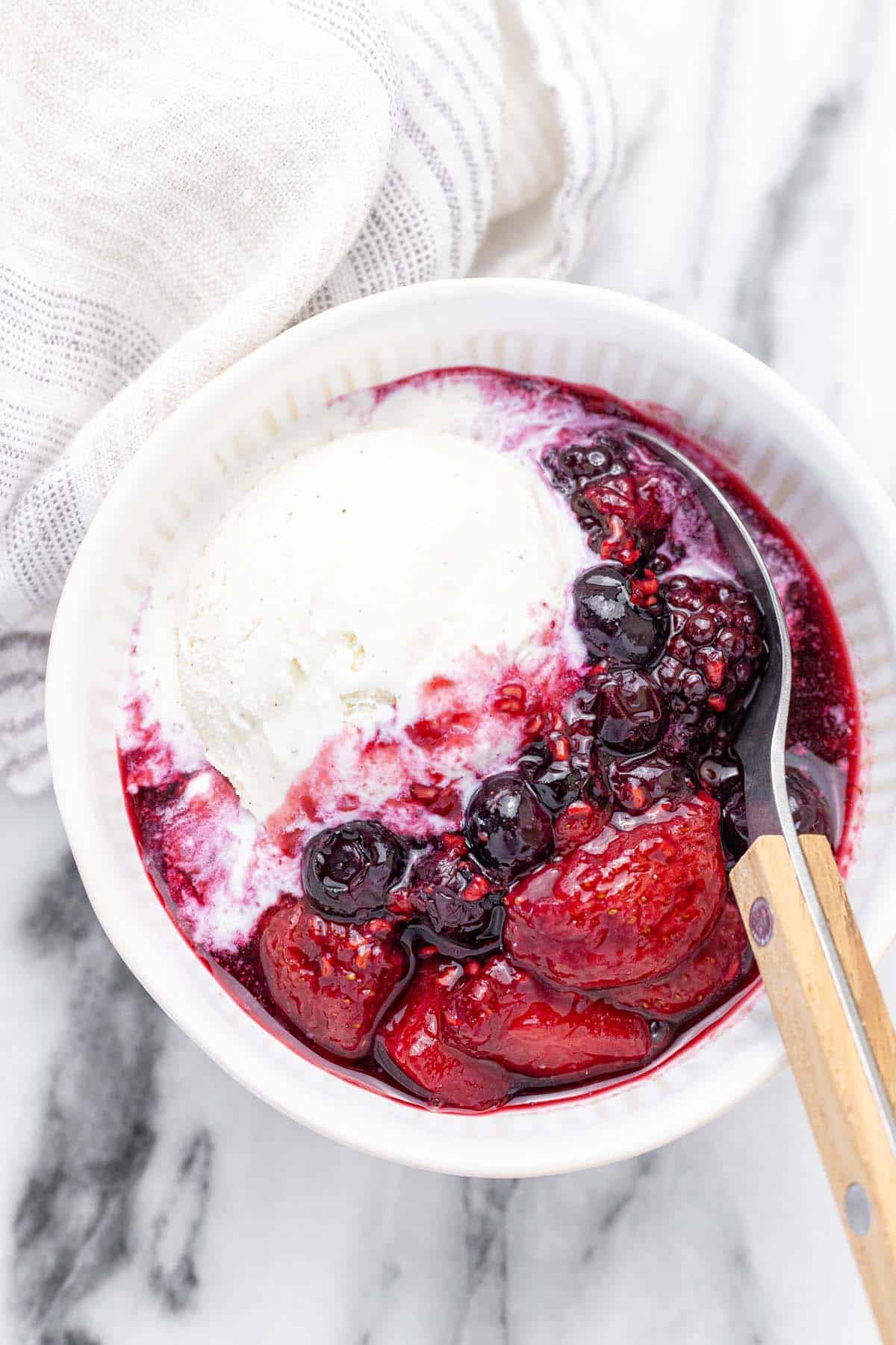 Bowls of vanilla ice cream topped with mixed berry compote.