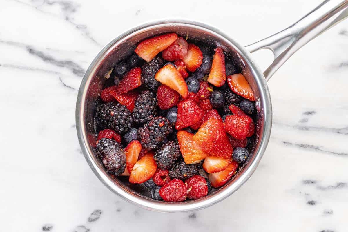 Small saucepan with berries combined with sugar, lemon zest, and lemon juice.