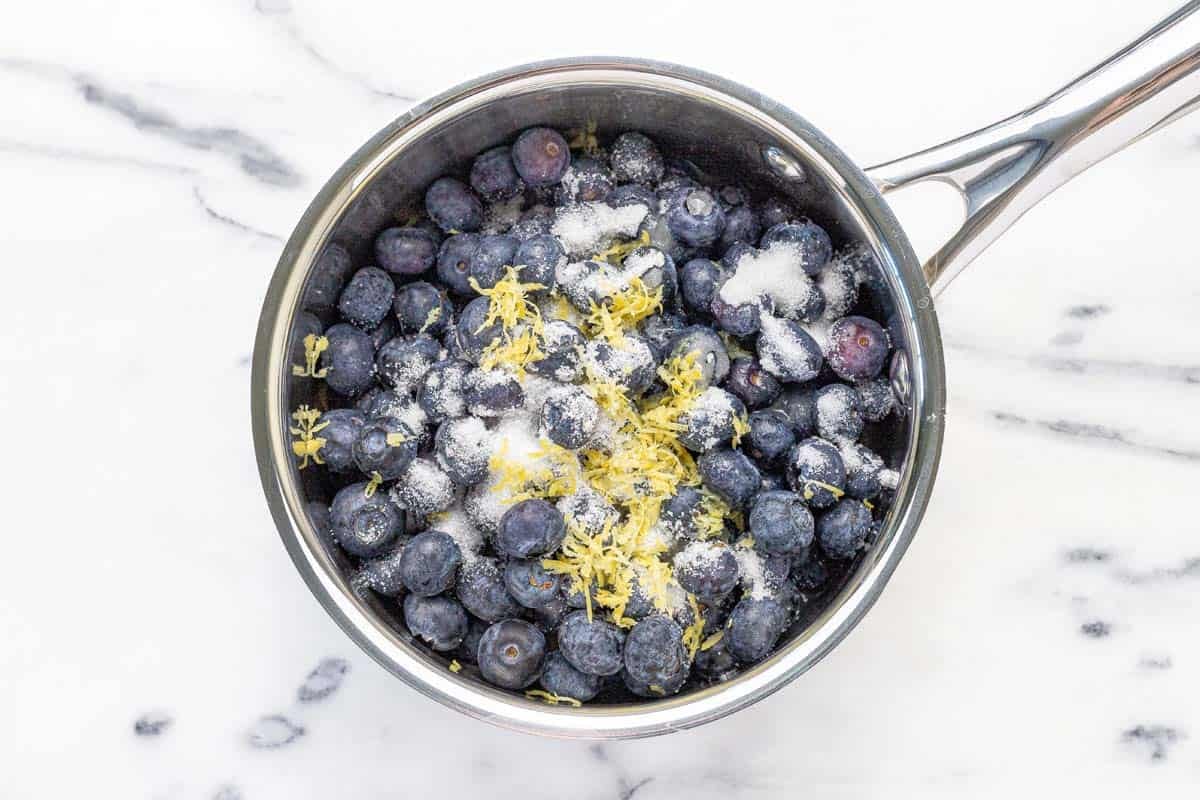 Saucepan filled with ingredients to make blueberry compote.
