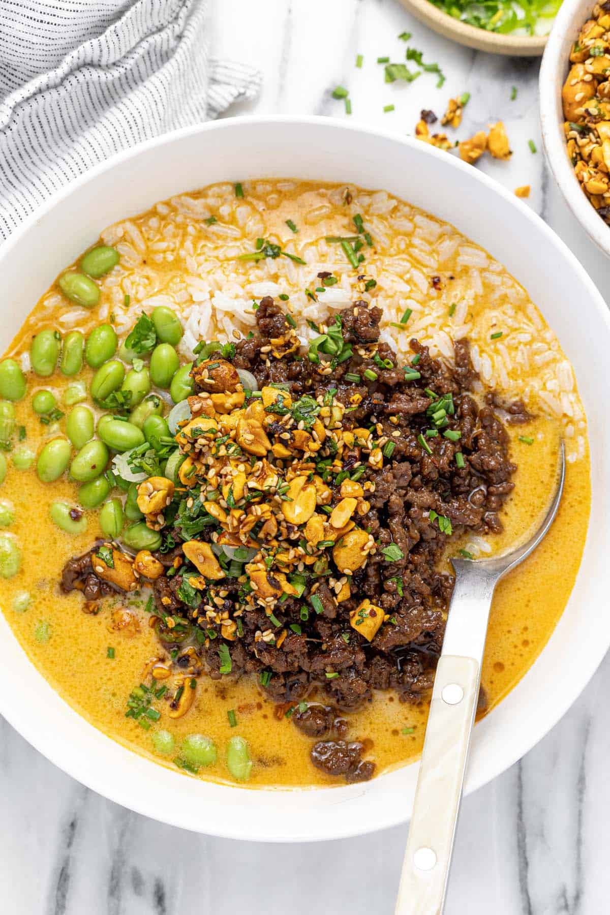 Bowl filled with brothy rice and ground beef topped with chopped peanuts.