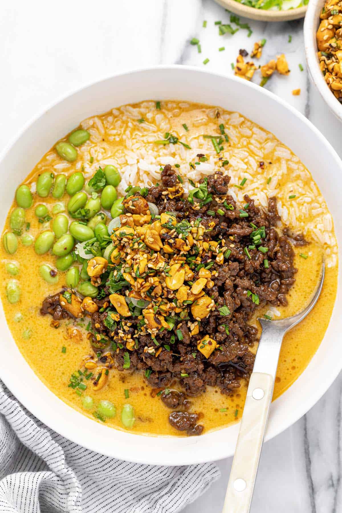 Bowl filled with brothy rice and ground beef topped with chopped peanuts.