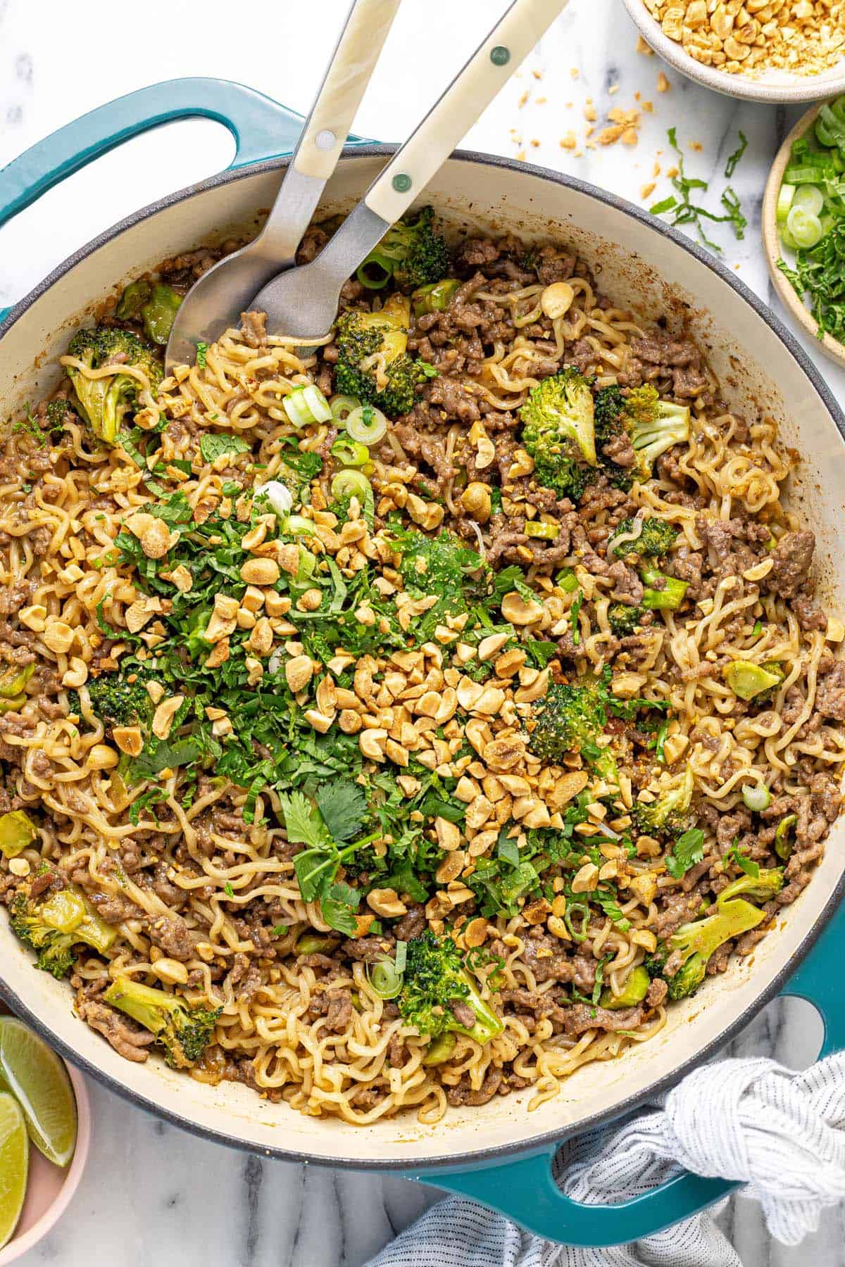 Large pan filled with sesame ginger ground beef and peanut noodles topped with herbs.